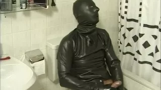 In Latex gehüllte Person masturbiert auf der Toilette