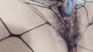 Amateurin in Netzstrümpfen spielt mit einem Vibrator.