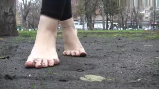 Girl shows her dirty feet on a park bench