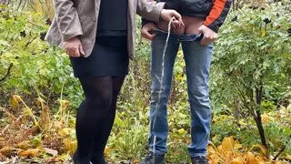 Hot milf in pantyhose and skirt holding guy's cock outdoors while pissing