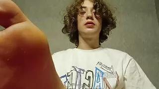 Curly twink shows his legs and jerks off his big dick cumming lots of cum