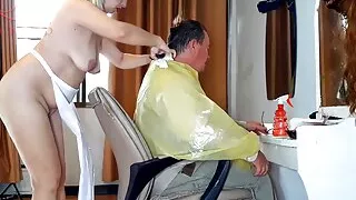 Nudist barbershop. Nude lady hairdresser in an apron. camera. The client is surprised. Scene 2