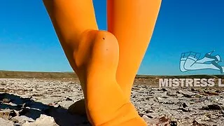 Barefoot walking by dried up lake in yellow pantyhose