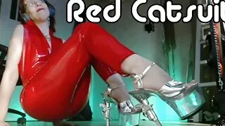 MistressOnline wearing a red lacquer catsuit and revolver high heels