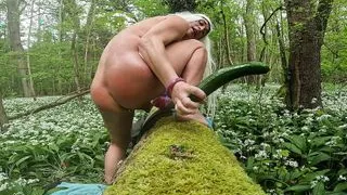 Tygra Blonde sissy eats a whole tasty cucumber in woods.