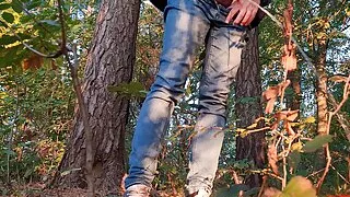 Guy pissing in the forest under a tree
