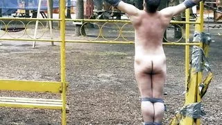 Crucified naked, tied and helpless guy in public park