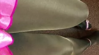 Tanned and black pantyhose layered legs satin pink miniskirt and heeled pink sandals.