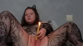 Passionate kitty in a mesh suit masturbates and inserts a burning candle into herself