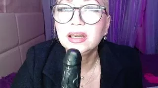 Slutty MILF in black coat and glasses sucks a big dildo furiously!