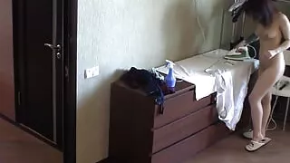 Nude tattooed brunette ironing her clothes in the house