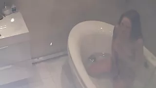 Horny brunette rubbing one out ahead of  a cold bathtub shower