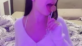 This busty lustful bitch sucks candy on the bed and dreams of a big dick