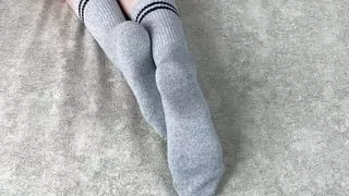Girl in bed strokes her legs in gray cotton socks