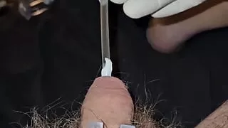 Inserting a catheter into the penis while wearing surgical gloves