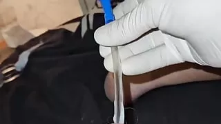 Wearing surgical gloves and inserting a catheter into the penis