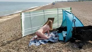 A young blonde wife is nude and masturbating on a British public beach