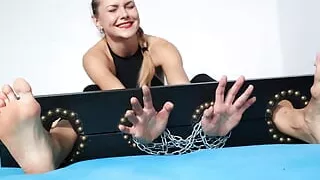Torturing her sexy feet locked in stocks