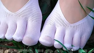 Goddess Feet in cute white socks with jeans on the spring grass field
