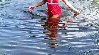 Swimming in lake in coral color summer dress and white sneakers. Wet dress. Wetlook transgirl