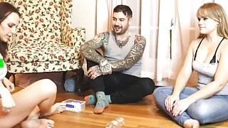 Two girls and one guy are playing a strip game of spin the bottle