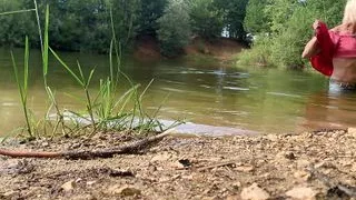 Trans-girl swimming in jeans and pink top in the lake..