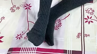 Girl in gray long socks on her legs caresses herself in bed
