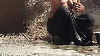 Indian sister-in-law is bathing in the open courtyard of the house, putting a finger in her burrow and rubbing the body, sister-in-law is washing the bathroom.