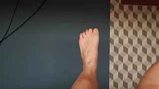 A fat man plays with his feet, naked in bed