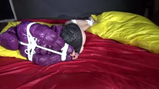 Watching Sexy Sonnja Wearing A Black Shiny Nylon Down Skirt And A Purple Downjacket Being Tied And Gagged With Ropes And A Ballgag On A Bed (Video)
