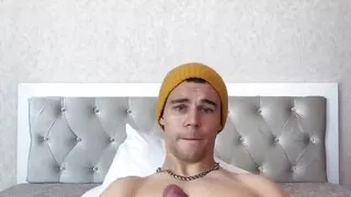 A Young, Strong Guy Jerks off a Big Dick Lying on the Bed