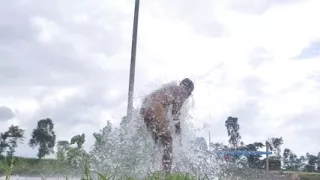 Indian boy stripped naked and bathed in a field