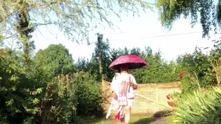 In an outfit with a pink nightgown and a sheer white dressing gown with a parasol