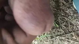 The boy put out his fire in the woods.