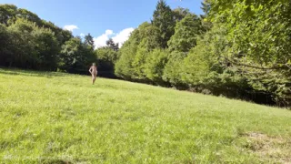 Nude posing in a meadow locked in a steel chastity cage