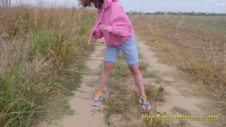 Hipster girl with a hoodie pee trough her jeans and pee next to the wheel of the car