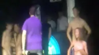 2 russian couple have a striptease game on stage in a disco