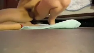 Mädchen mit massiv behaarter Muschi masturbiert mit einem Vibrator auf dem Boden