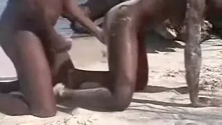 Ebon couple having a doggy style sex on the sand