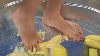 Asiatisches Mädchen zerquetscht Bananen mit bloßen Füßen