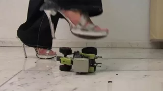 Slim girl crushes toy tractor with ass and shoes.