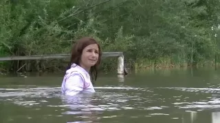 girl with fully clothes swims in lake