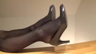 Footplay in schwarzen Strumpfhosen und grauen Pumps