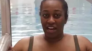 BBW Schwarze Frau setzt eine rosa Latex-Badekappe auf