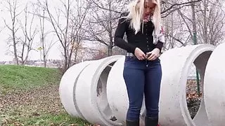 Blonde pisses on field behind concrete rings 25641