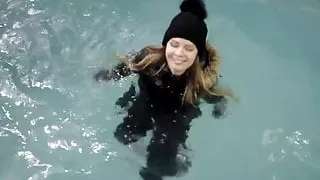 wetlook girl with winter clothes swims in the pool