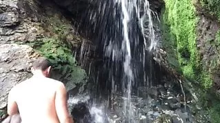Public nudity, nudism. Naked at a beach waterfall.