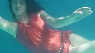 Red dressed mermaid Rusalka swimming in the pool