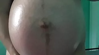 Asian girl oils huge pregnant belly