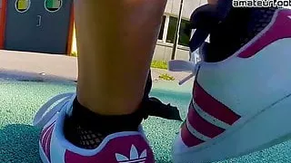 Girl in red Adidas Superstars does shoeplay, dipping fishnet socks